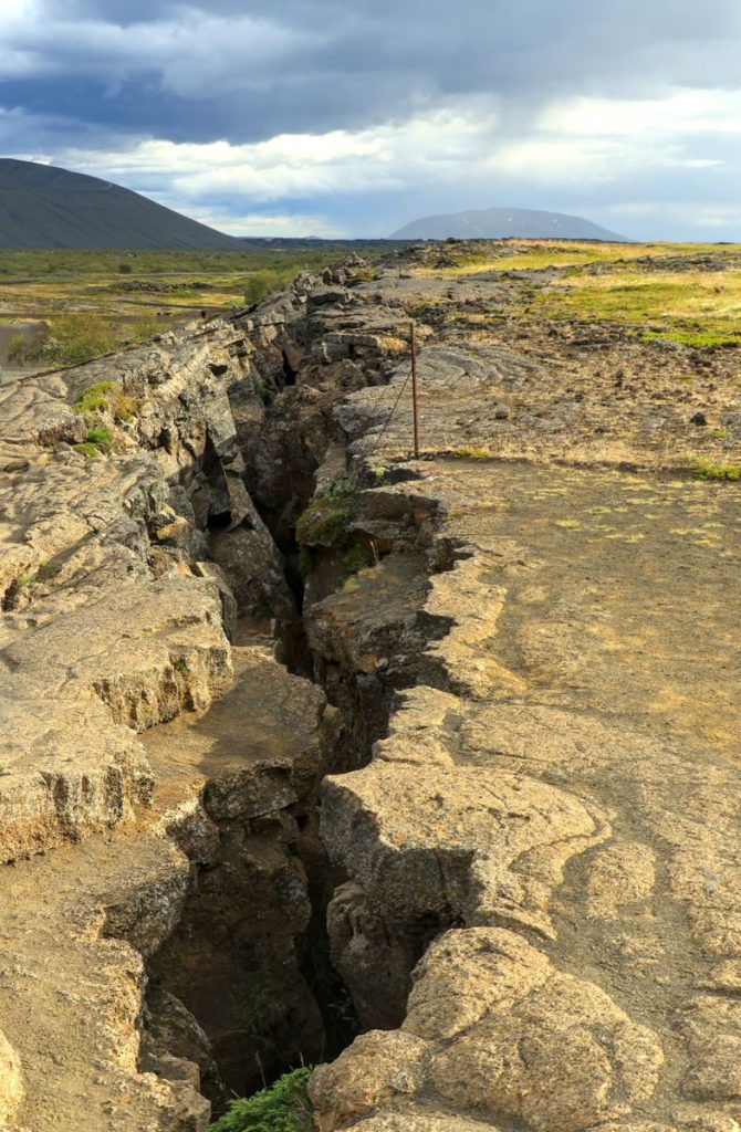 Explore the rugged terrain of a dramatic geological rift on an island under a moody sky.