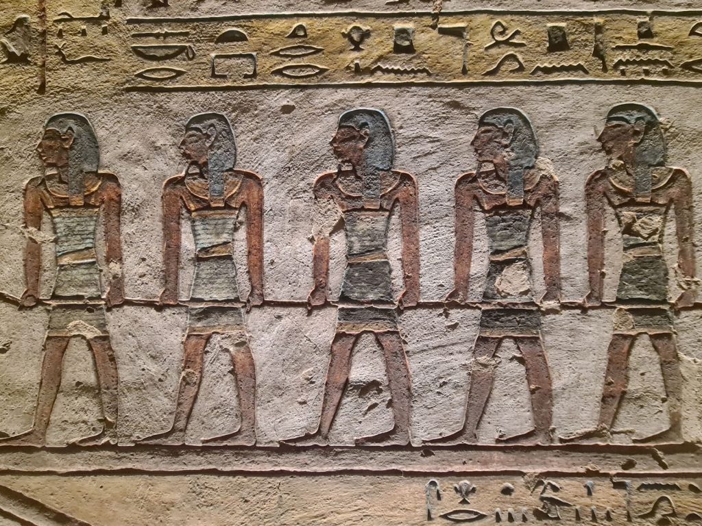 Stone relief of ancient Egyptian figures and hieroglyphs from Luxor, Egypt, showcasing historical artistry.