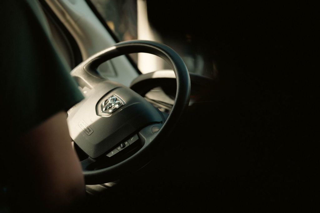 Detailed view of a vehicle's steering wheel with sunlight casting shadows inside the car.