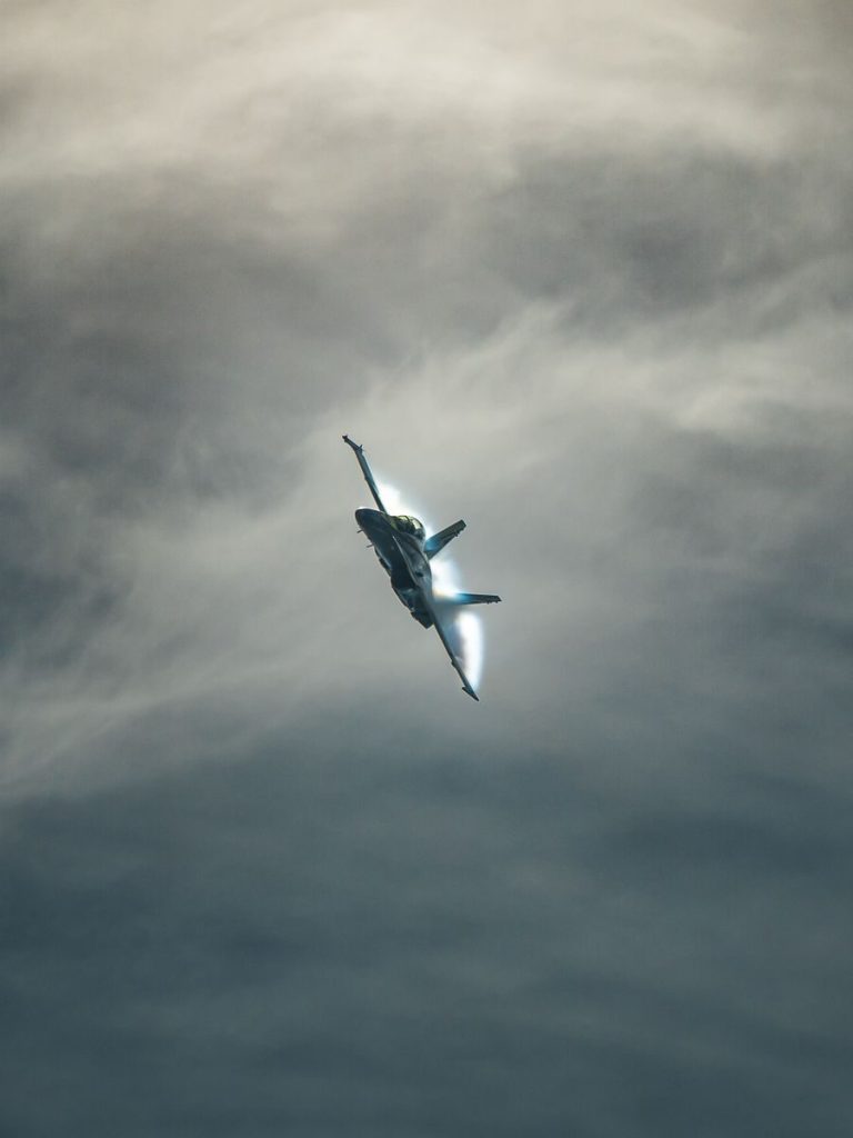 A fighter jet soars through a dramatic cloudy sky, highlighting its powerful maneuvers.
