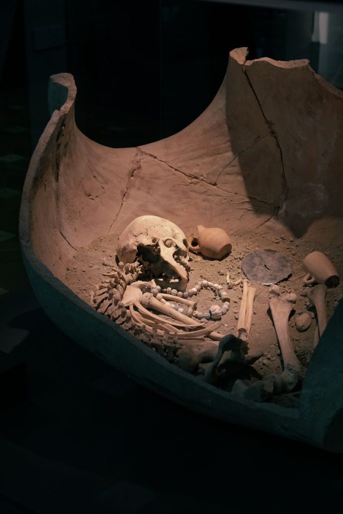 Artifact-laden burial site with human skeleton in clay chamber, showcasing history.