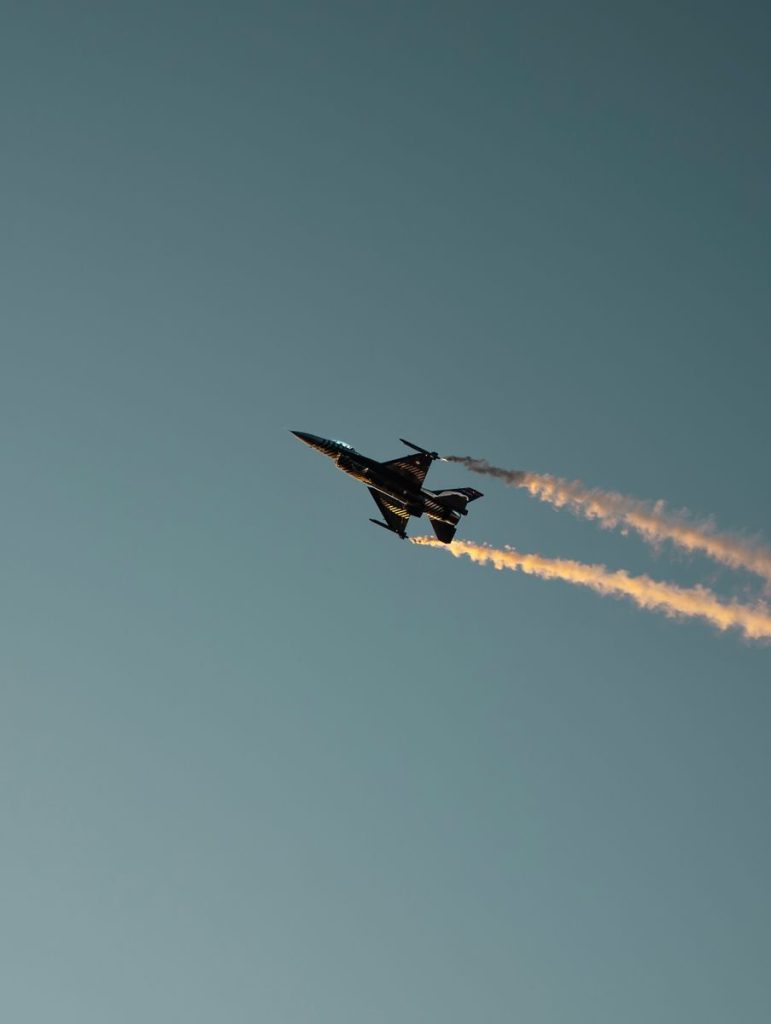 A fighter jet performs a stunning aerobatic maneuver against a clear sky.