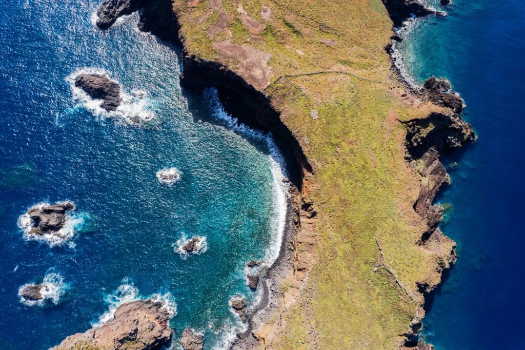 Breathtaking aerial view of Madeira's coastline with rocky formations and blue ocean.