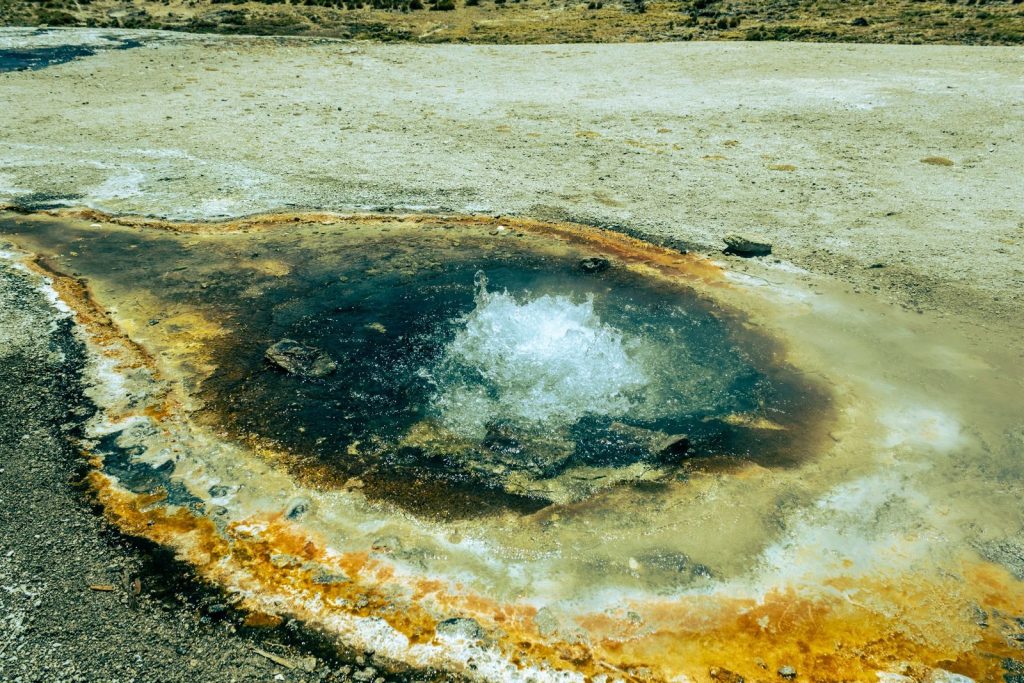 A bubbling hot spring surrounded by colorful mineral deposits in a geothermal area.