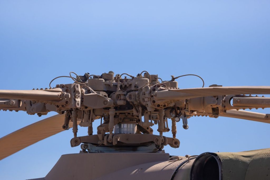 Detailed view of helicopter rotor blade assembly under clear blue sky.