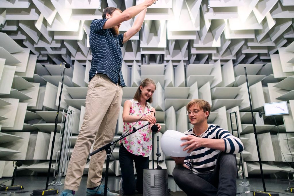 Engineers working together in a soundproof room to conduct acoustic testing with modern equipment.