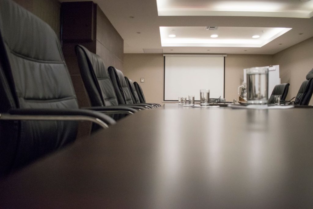 Empty conference room with black chairs, projector, and glasses on table. Ideal for business meetings.