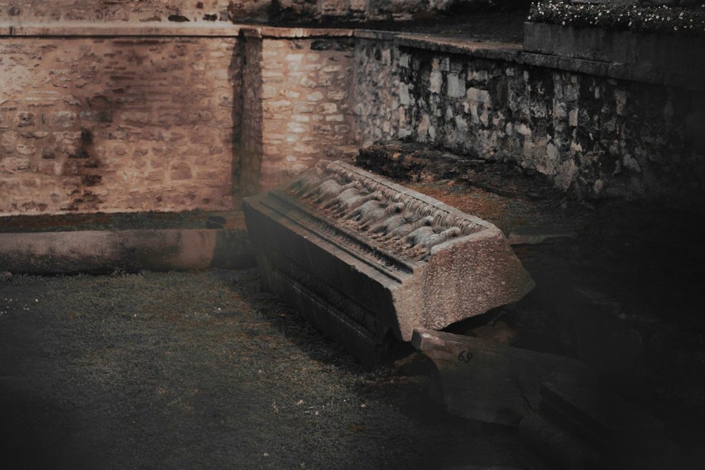 A tilted coffin lies partially submerged in water.
