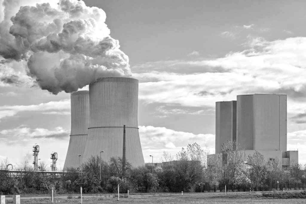 A black and white photo of a factory with smoke coming out of it