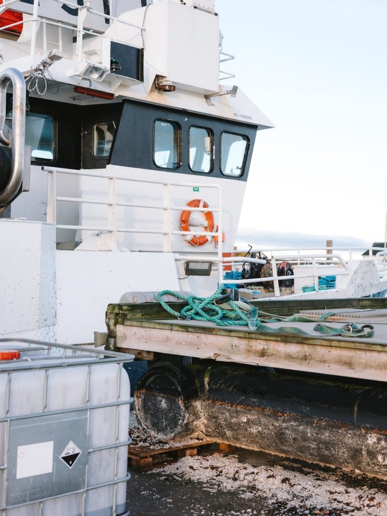 White fishing boat docked at a pier with supplies