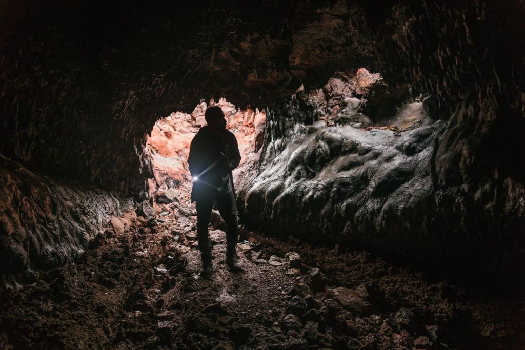 Silhouette of a person exploring a dimly lit cave with a flashlight, emphasizing adventure.