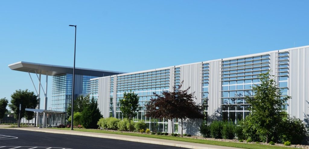 Large modern building with trees and clear blue sky.