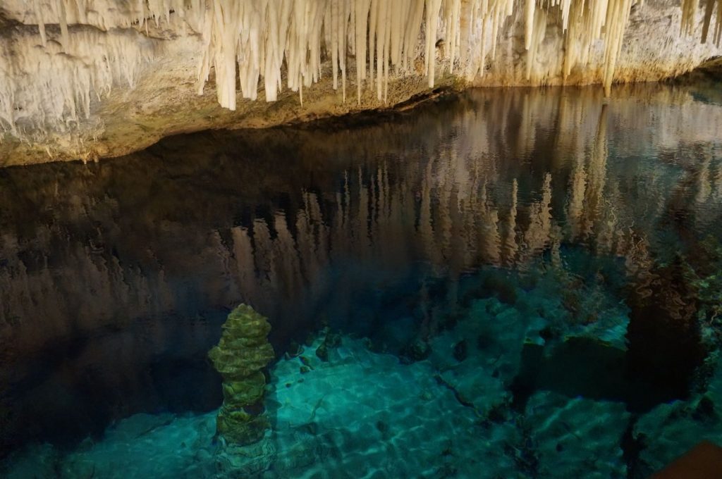 Explore the beauty of a natural underground cave featuring stalactites and crystal clear water.