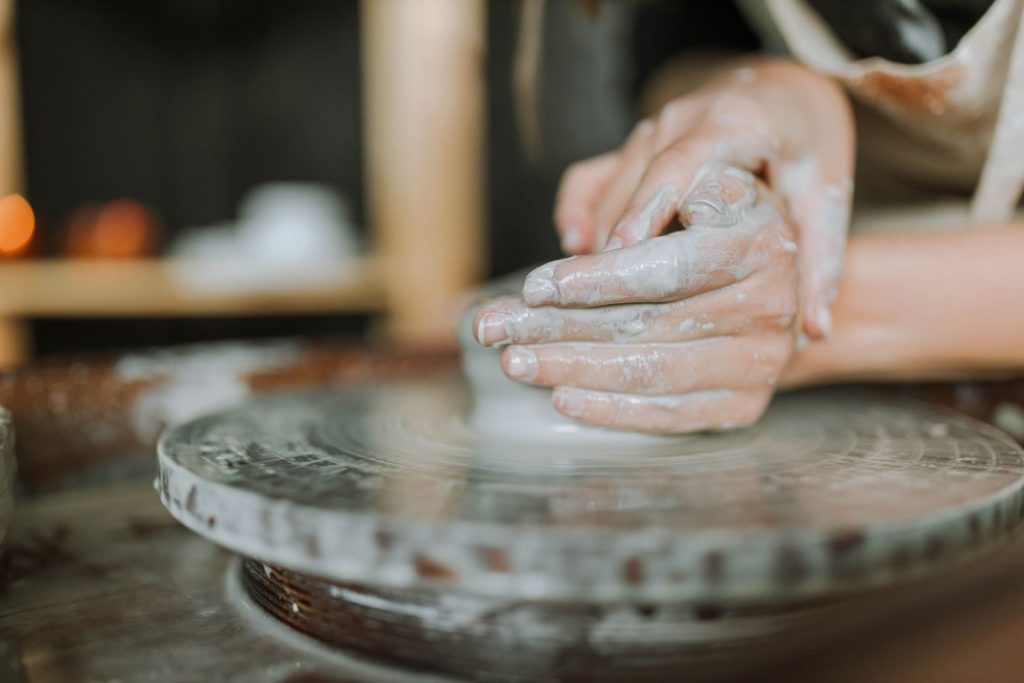 Hands shaping clay on a potter's wheel, focusing on craftsmanship and creativity.