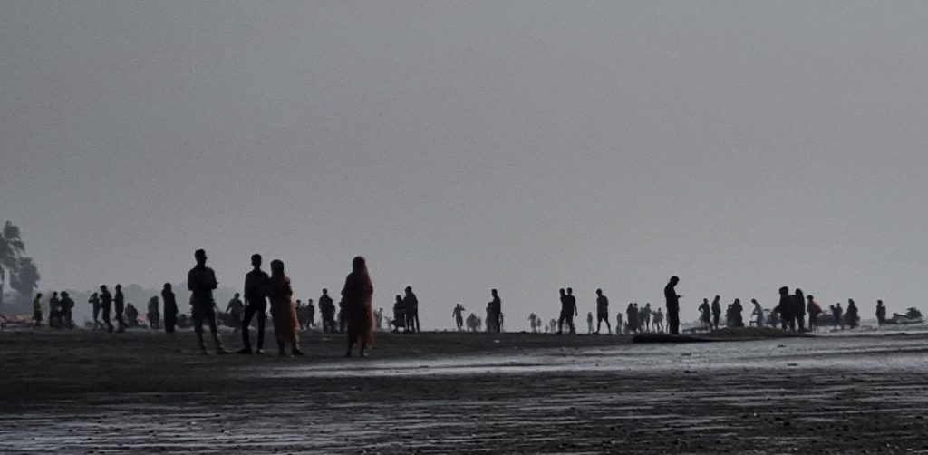 a group of people standing on top of a sandy beach