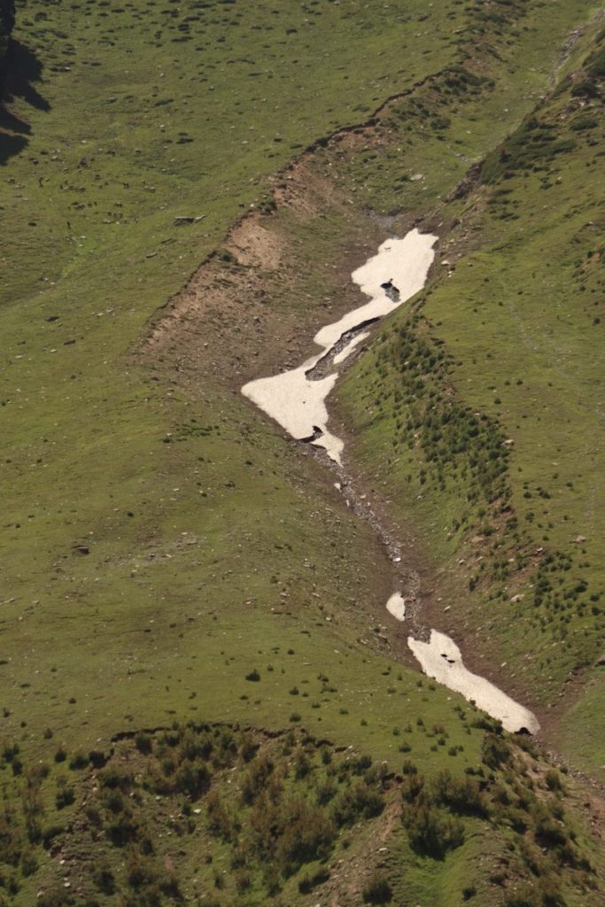 An aerial view of a stream running through a grassy field