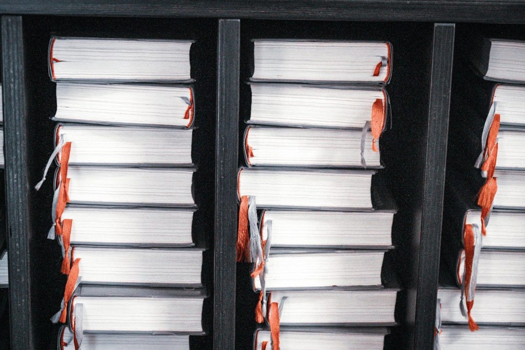 Stacks of white books with orange ribbons on shelves