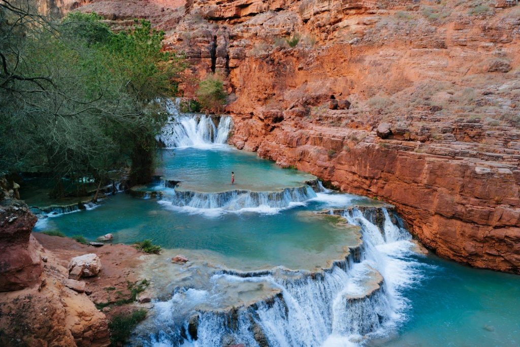 Turquoise waterfalls cascade down red rock canyon walls