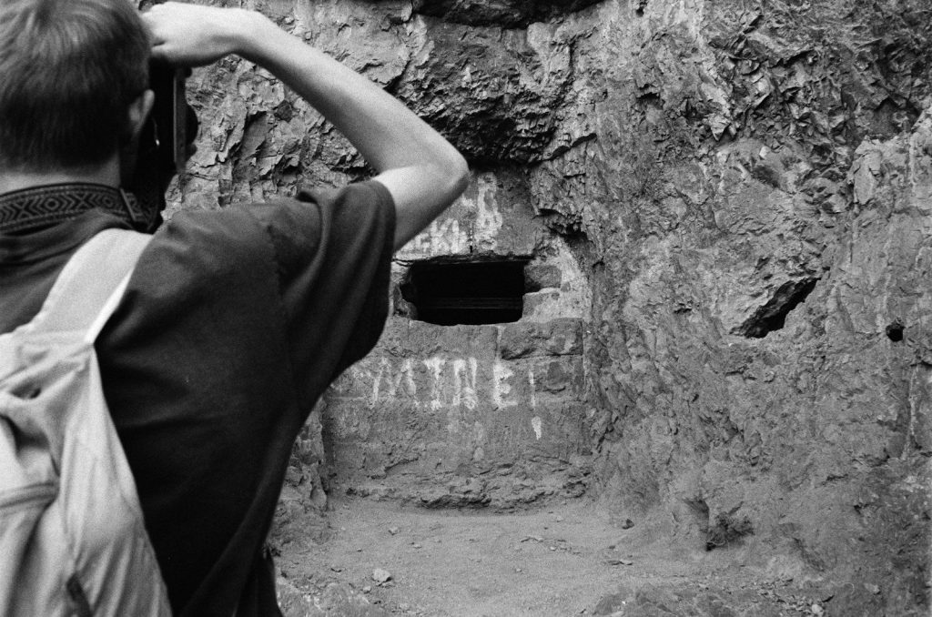 Man taking a picture of a cave entrance.