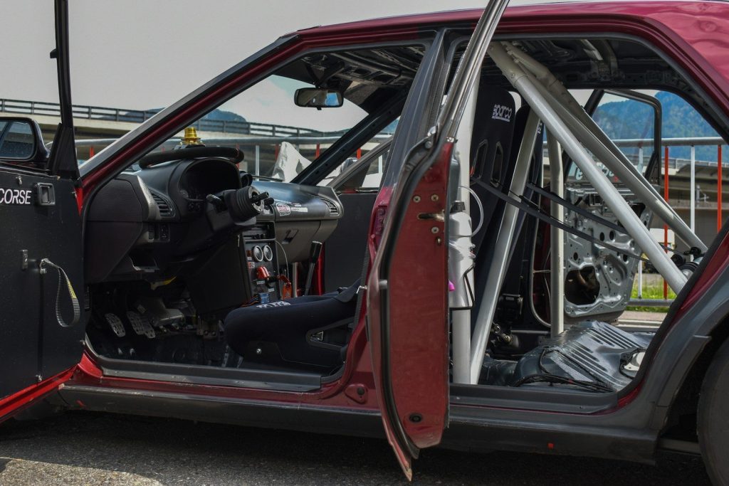 a red car with its door open and a motorcycle in the back
