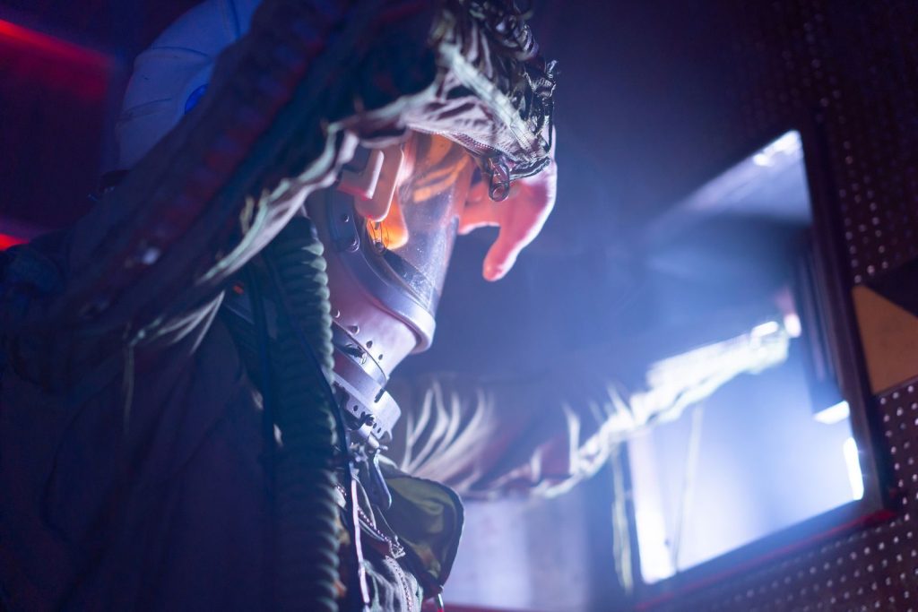 A space traveler in a futuristic suit explores a sci-fi spacecraft, bathed in dramatic lighting.