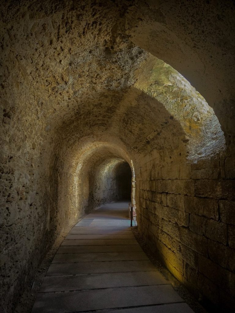 Ancient stone tunnel with arched ceiling and wooden floor