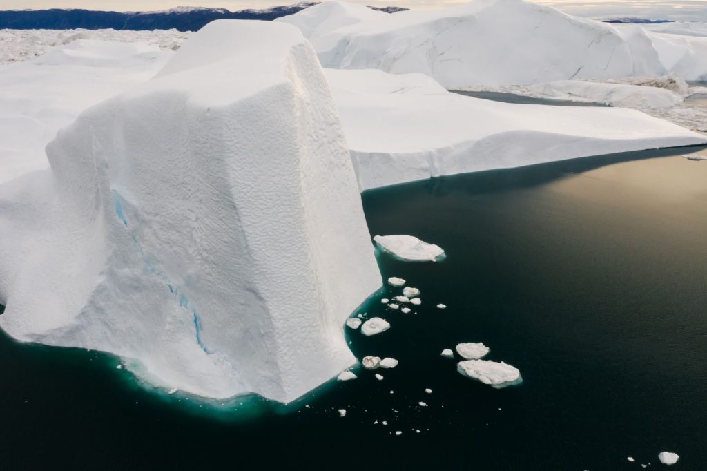 A stunning aerial shot capturing vast icebergs in frigid Arctic waters during daylight.