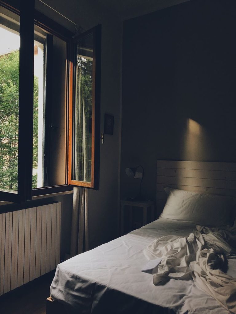 A serene bedroom scene with white linen and an open window, perfect for relaxation.