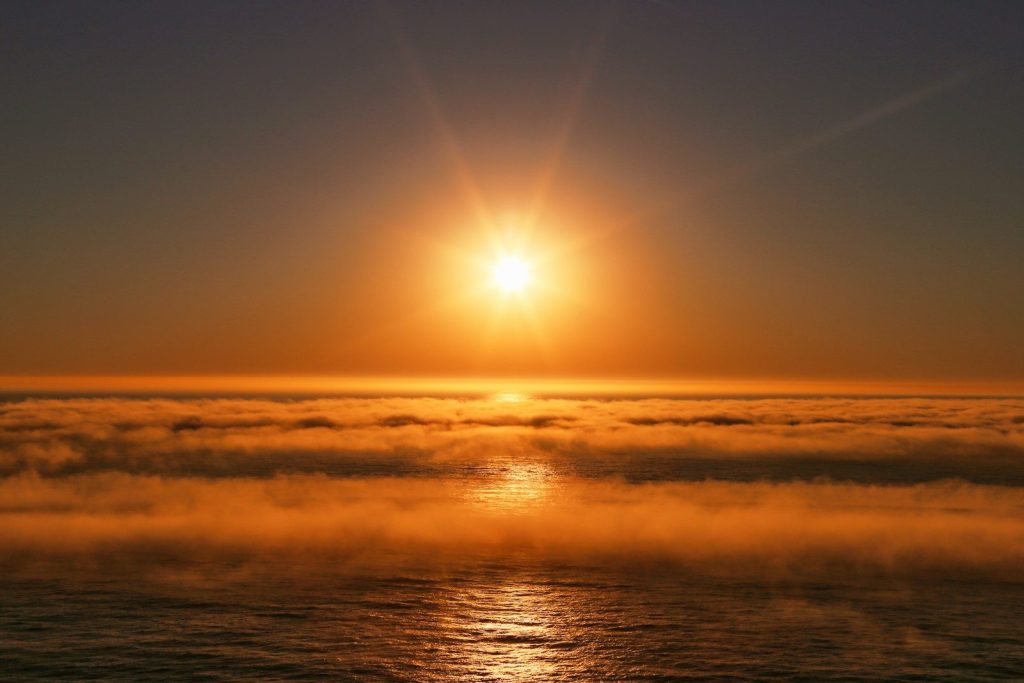 Golden sunrise over misty ocean waters
