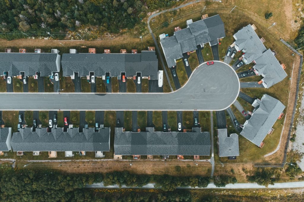 Drone shot of a modern suburban cul-de-sac featuring rows of townhouses and parked cars.