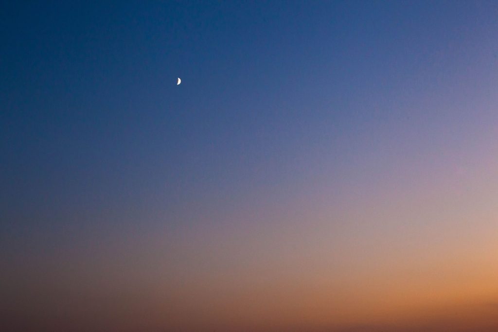 Minimalist image of a twilight sky with a crescent moon, creating a tranquil atmosphere.