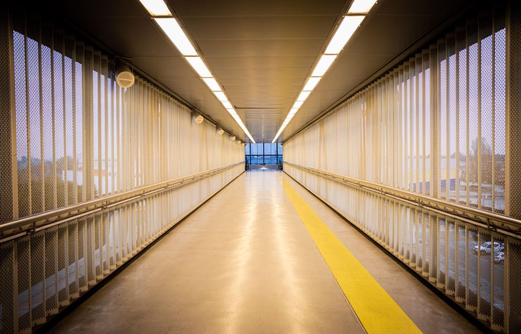 A brightly lit modern hallway with industrial design and a yellow guideline.