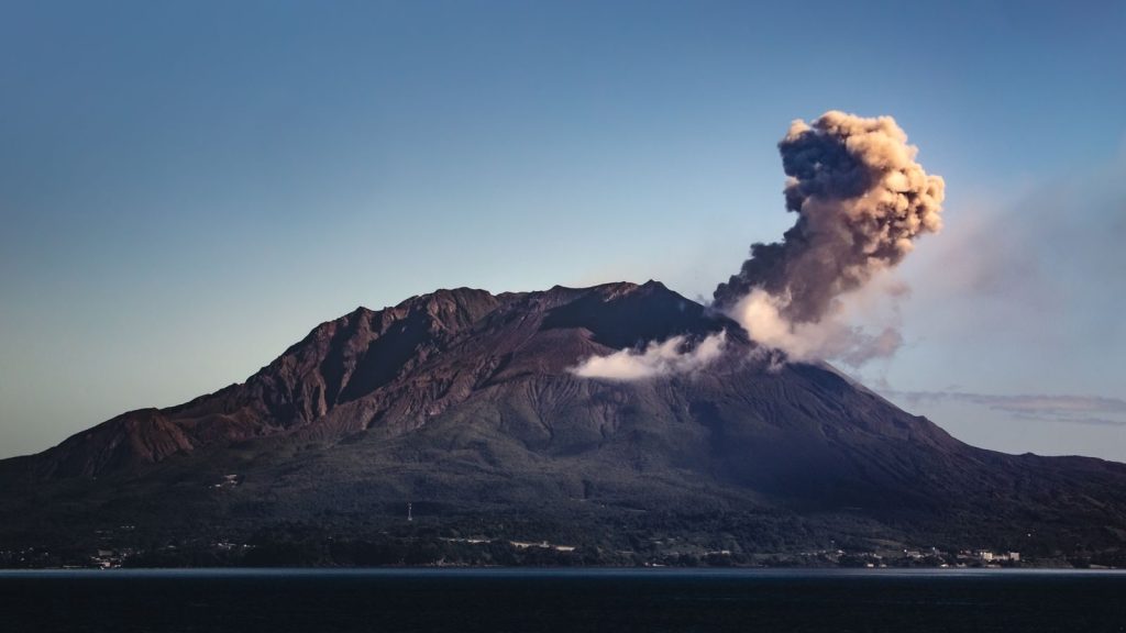 Spectacular eruption of Sakurajima Volcano with ash plume rising above Kagoshima Bay at dawn.