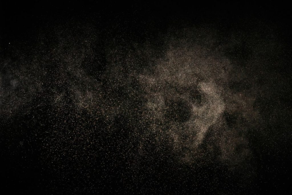 Abstract image of fine particles floating against a black background.