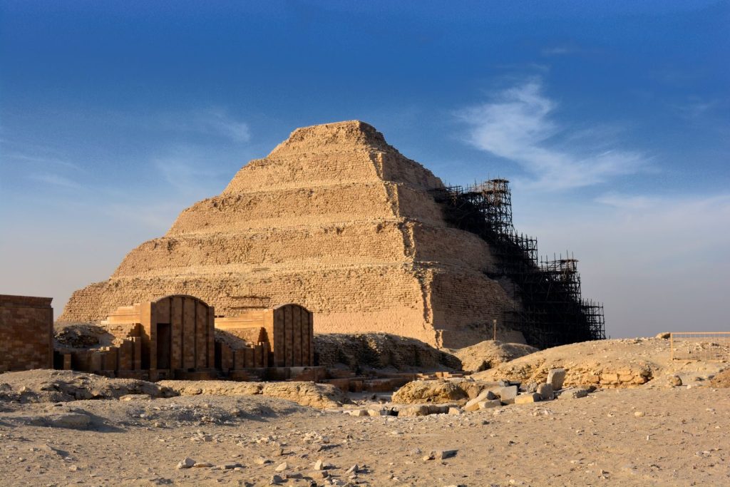 Step Pyramid of Djoser in Saqqara under restoration with clear blue sky.