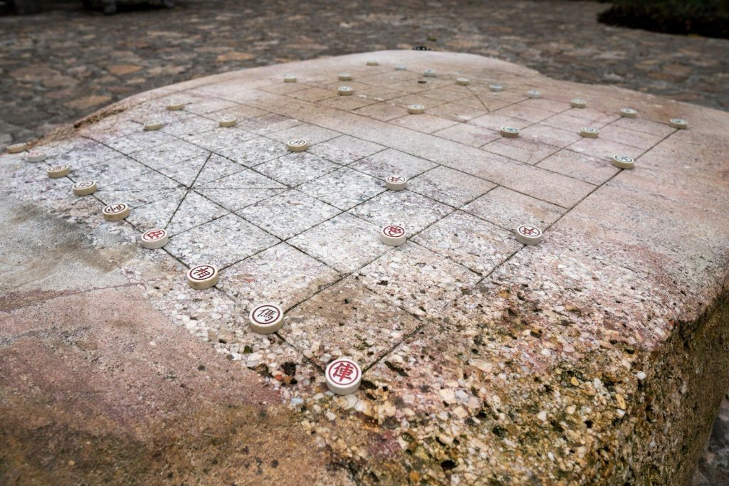 Stone chessboard with pieces on rough surface