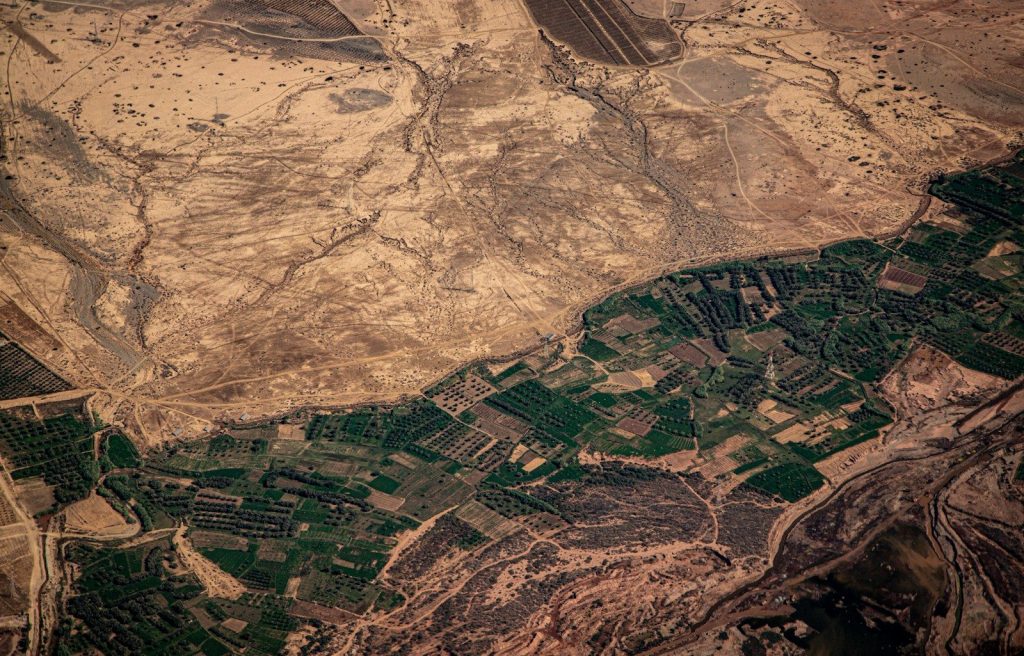 Aerial view of cultivated fields next to arid land.