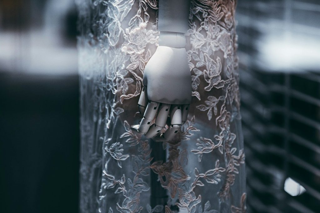 Mannequin hand holding delicate white lace fabric.