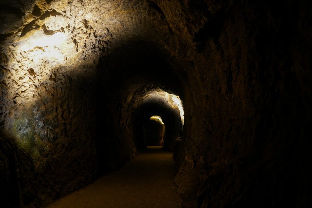 A dimly lit cave tunnel with rough textured walls.