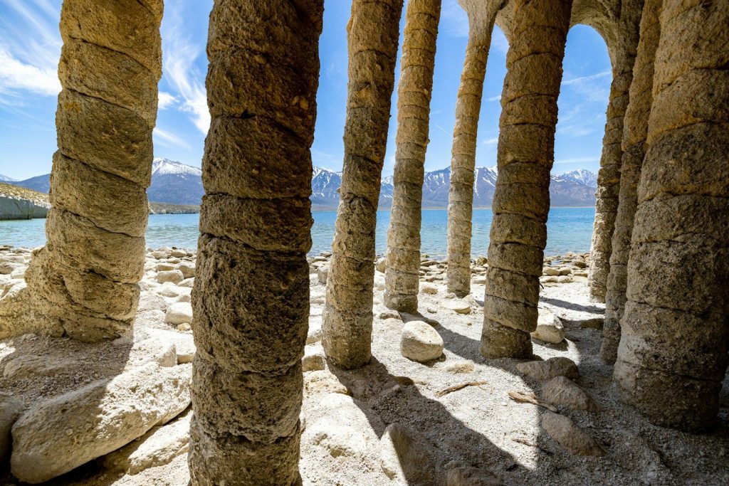 a row of stone pillars next to a body of water