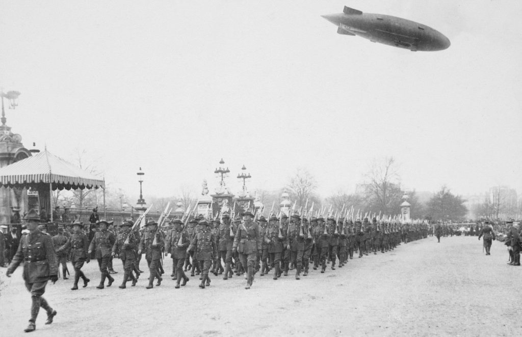 Soldiers marching in formation with airship overhead