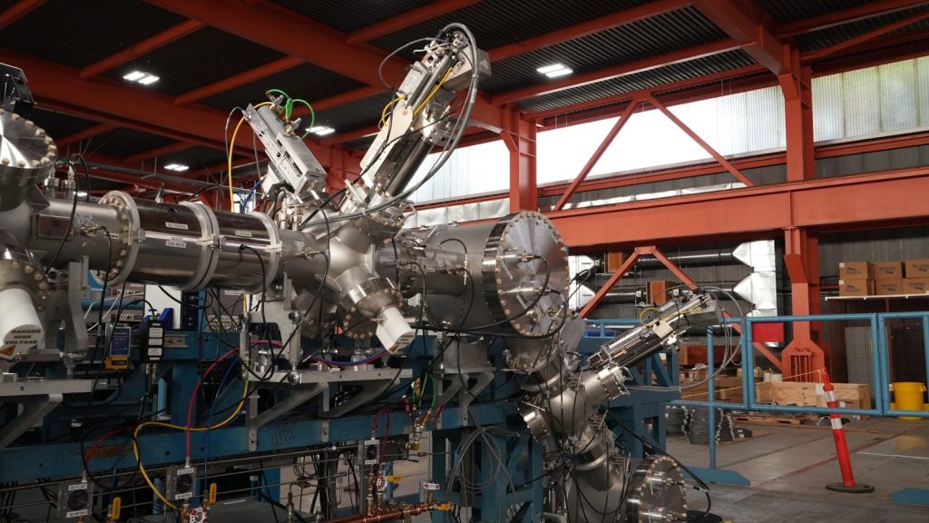 Complex scientific machinery inside a large industrial facility.