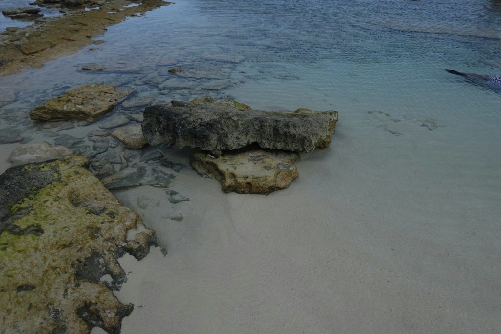 Rocks and clear water on a sandy beach.