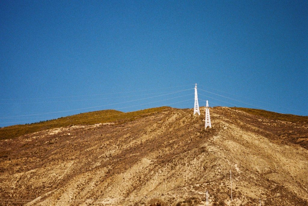 Two tall towers on a grassy, barren hillside