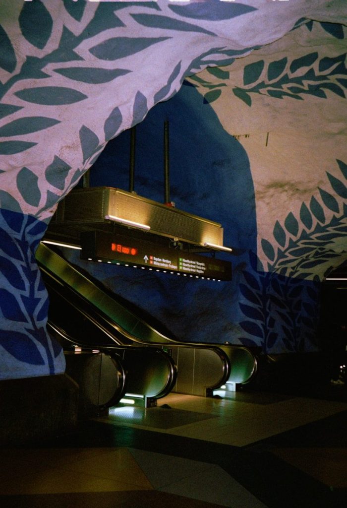 Escalator descends into a colorful, painted subway station.