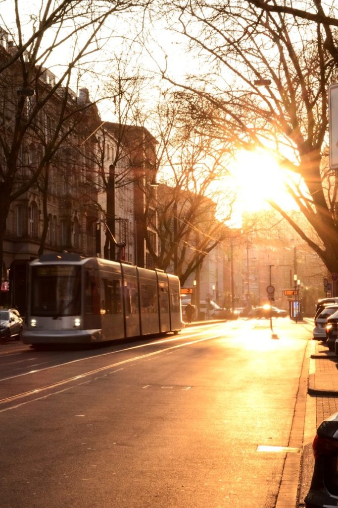 A tram rides through a street at sunset.