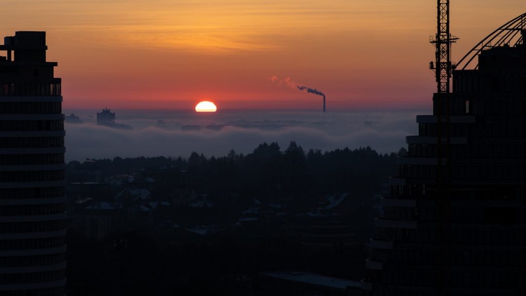 The sun is setting over a city with tall buildings