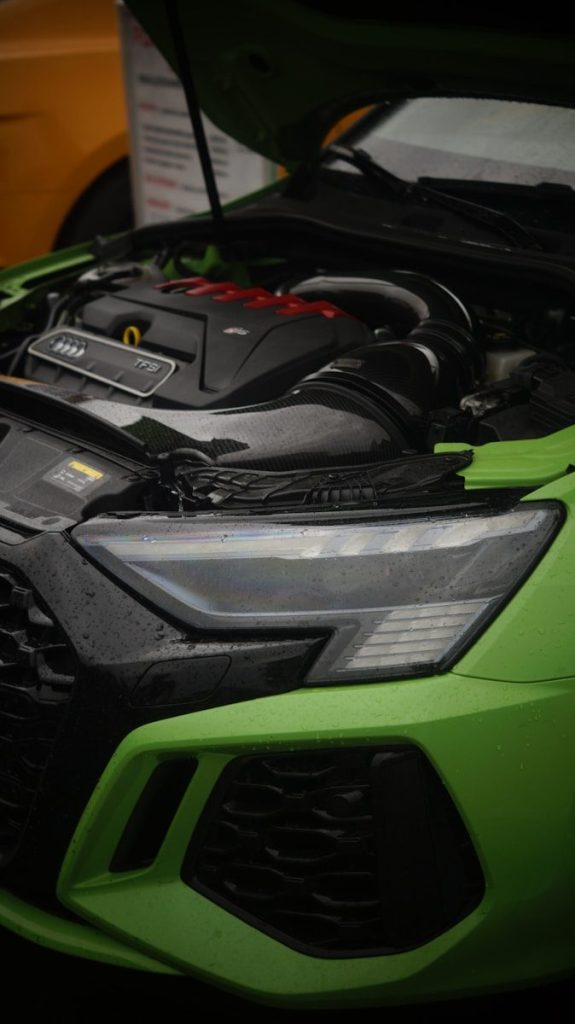 A green sports car with its hood open