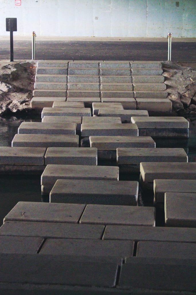 a walkway made out of cement blocks next to a body of water