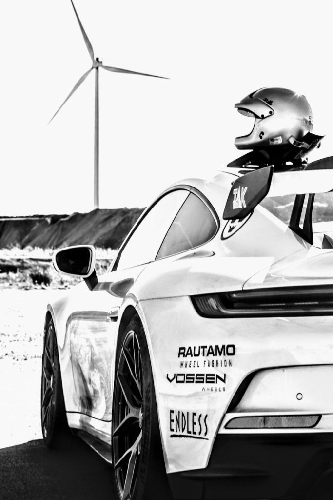 a white sports car with a wind turbine in the background